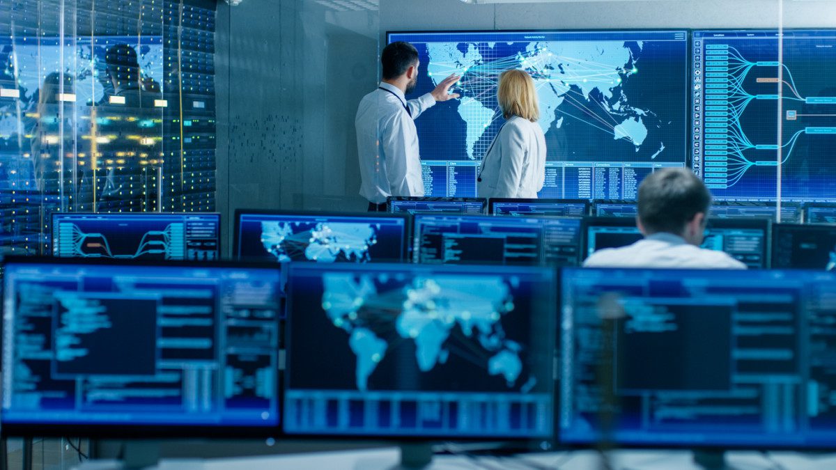 In the System Monitoring Room Two Senior Operators Work on a Big Interactive Map. Facility is Full of Screens Showing Technical Data.