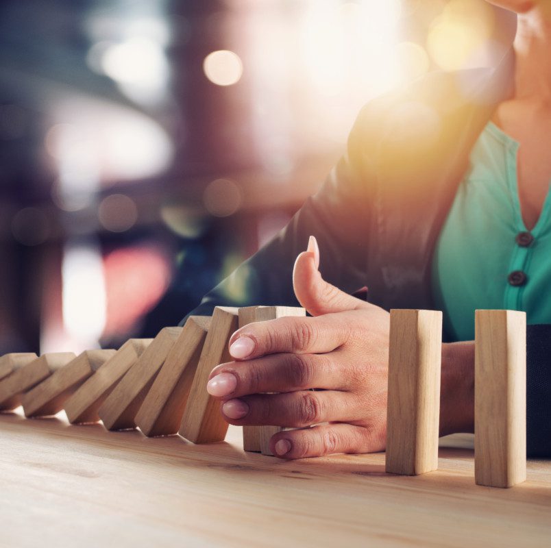 Businesswoman stops a chain fall like domino game. Concept of preventing crisis and failure in business.
