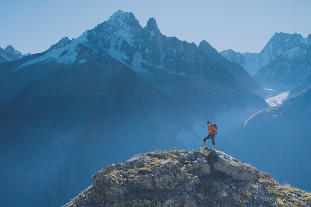 A hiker on top of a rocky summit in the mountains of the Alps